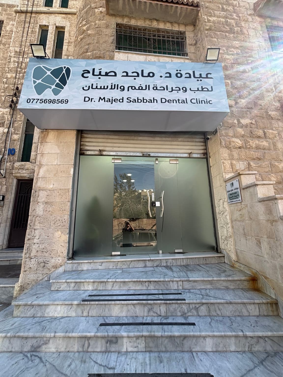 واجهة عيادة د. ماجد صباح لطب وجراحة الفم والأسنان: لوحة الاسم والشعار فوق باب زجاجي ودرجات رخامية واجهة عيادة د. ماجد صباح لطب وجراحة الفم والأسنان: لوحة الاسم والشعار فوق باب زجاجي ودرجات رخامية